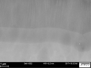 Abb. 3: REM-Aufnahme (Querschliff) des 2-stufigen Eloxal-Schichtaufbaus Typ „Sperrschicht“ (ohne Metallisierung). Im Bild unten das Aluminium-Grundmetall, oben die porige, unverdichtete Eloxalschicht, in der Mitte die auf rund 2 µm verstärkte Sperrschicht. Die Abbildung zeigt quasi den Idealzustand, welcher nur mit Reinst-Aluminium erzielt werden kann