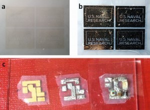 Bild a) NRL-Logo auf Nanocellulose-Substrat, Ink-Jet Printing mit Pd-basierter Tinte; b) Auf das Tinte-Muster stromlose Verkupferung und dann Vernickelung und c) anschließendes Löten