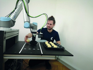 Timon Hitz von Wandelbots lernt im IoT-Labor vom Smart Systems Hub einen Roboter an, Teiglinge auf ein Blech zu sortieren