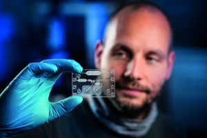 Florian Schmieder vom Fraunhofer IWS überprüft den Prototyp einer komplexen In-Vitro-Diagnostik-Kartusche zur Blutseparation. Das Fraunhofer IWS entwickelt im Projekt SIMPLE-IVD mit Industriepartnern neue Methoden zur kosteneffizienten Produktion solcher Kartuschen