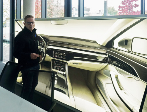 Markus Dahlhaus vor einer Darstellung des Fahrzeuginnenraums eines Audi A8
