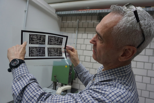 Ulrich Urban mit einem Leiterplattenbild, das die Schaltungen und die Belichtungsmaske zeigt. Anhand dieser Maske wird selektiv galvanisiert