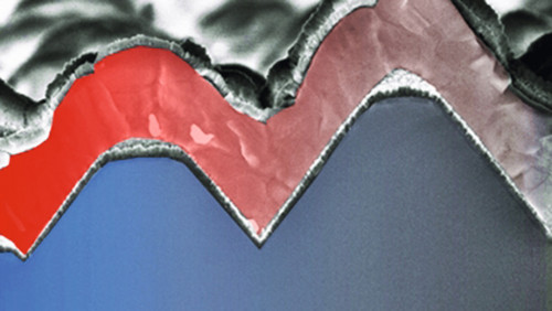 Eine Schicht Perowskit (rot) bedeckt den welligen Untergrund einer Silicium-Solarzelle. Beide Schichten empfangen mehr Licht als eine allein