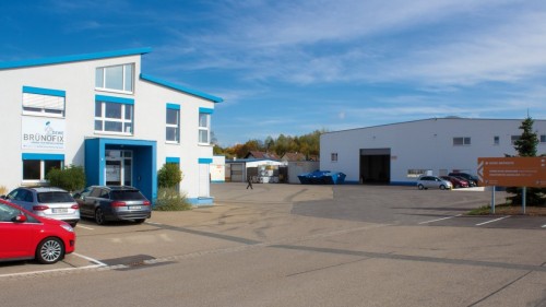Das Verwaltungsgebäude im Vordergrund mit einer der Produktionshallen im Hintergrund
