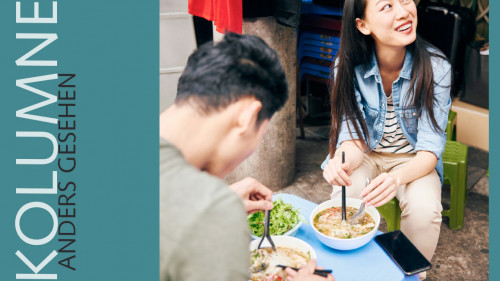 Junges Paar beim Genuss der vietnamesischen Suppe ‚Pho‘, einer kräftigen Suppe mit Reisnudeln, Rindfleisch und Kräutern, traditionell gewürzt mit Kardamom, Sternanis, Zimt und geröstetem Ingwer – ein Dauerbrenner in Hanois Straßenküchen